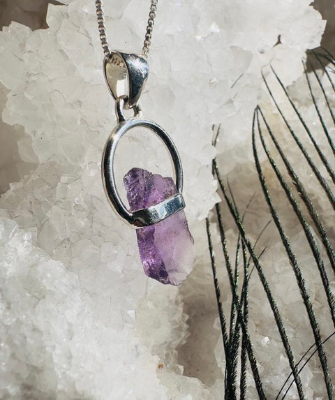 Amethyst pendant in a silver setting on a crystal background