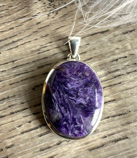 Purple marbled pendant in a silver setting on a wooden surface