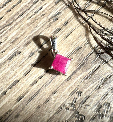 Pink gemstone pendant on a textured surface