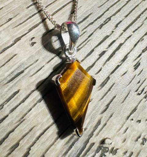Tiger's eye pendant on a chain against a textured surface