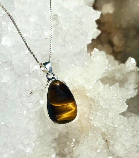 Tiger's eye pendant on a silver chain against a crystal background