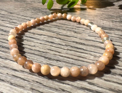 Beaded necklace on a wooden surface with a plant in the background