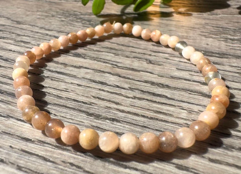 Beaded necklace on a wooden surface with a plant in the background