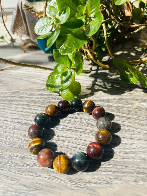 Multicolored beaded bracelet on a wooden surface with green leaves in the background